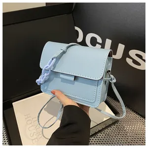 Dettaglio di borsa a tracolla in pelle azzurra con catena decorativa e cuciture fini