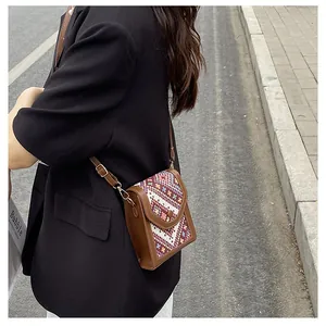 Detail of crossbody bag featuring ethnic geometric weaving and brown leather trim