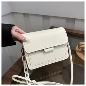 Dettaglio della borsa a tracolla crema con catena elegante e cinturino in pelle