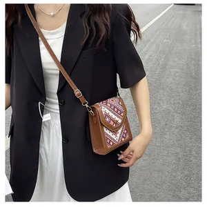 Detail of vintage brown crossbody bag featuring ethnic geometric woven flap and snap closure