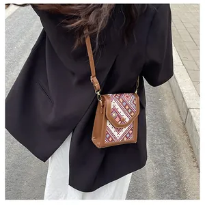 Close-up of retro crossbody phone bag featuring brown leather and ethnic woven pattern