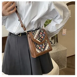 Brown leather crossbody bag with ethnic geometric weave pattern on model in cozy room