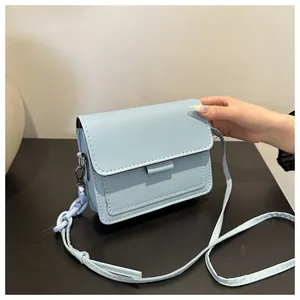Dettaglio di una borsa a tracolla azzurra con catena decorativa in plastica viola