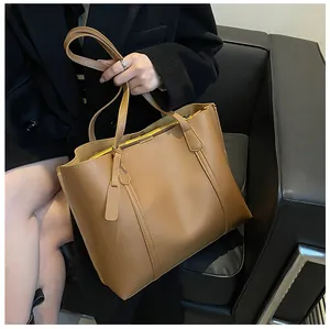 Bruine kunstlederen shopper met dubbele handgrepen en riem over een zwarte blazer