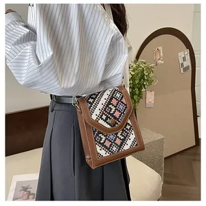 Close-up of geometric ethnic woven pattern and gold metal hardware on crossbody bag