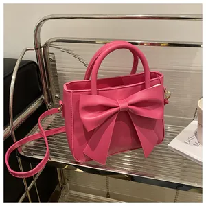 Detail view of pink handbag featuring a large bow and detachable shoulder strap