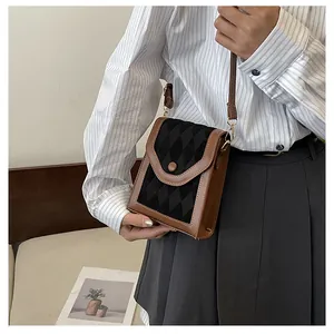 Close-up of a vertical mini crossbody phone bag with black quilted texture and brown trim