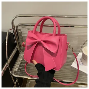 Detailed view of the fuchsia bow handbag featuring gold hardware and a long strap