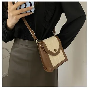 Detailed shot of retro patchwork crossbody phone bag featuring cream quilted fabric and brown leather