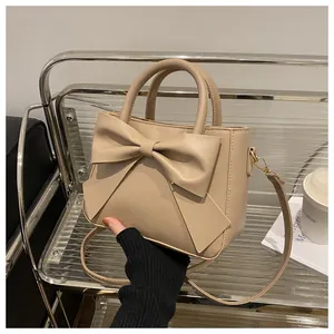 Close-up of elegant beige bow handbag with gold metal clasp on a designer shelf