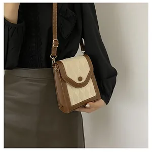 Detail of vintage beige quilted fabric and brown leather crossbody bag with gold buckle