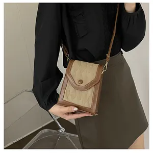 Close-up of a vintage beige patterned phone bag with brown leather trim and golden hardware