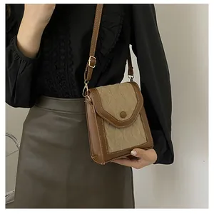Detail of vintage beige quilted crossbody bag with brown leather trim and button closure