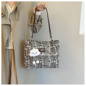 Detail of canvas tote with abstract lines, leather straps and plush cloud charm