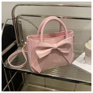 Detail of pink bow-knot handbag with gold hardware on a display shelf with lifestyle props