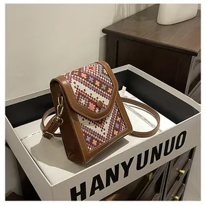 Detail of vintage ethnic jacquard phone bag with brown leather trim and gold metal clasp