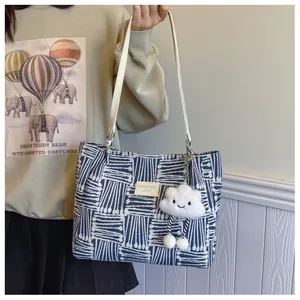 Close-up of blue and white geometric jacquard tote bag with leather straps and plush charm