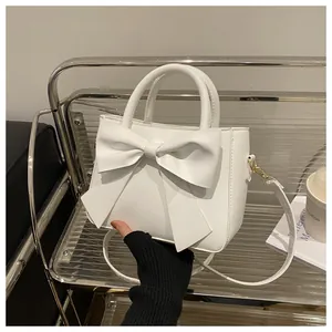 Detail of white PU leather mini bag with bow accent on a stylish glass shelf