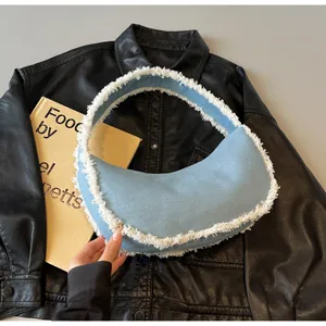 Detail of light blue denim crescent hobo bag with white frayed edges on leather
