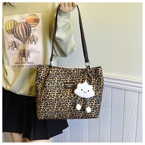 Detail of leopard print tote bag with leather strap and plush white cloud charm