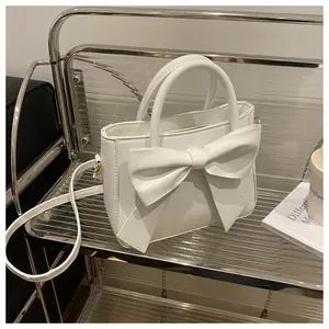 Detail of white minimalist handbag with large bow decoration and detachable strap