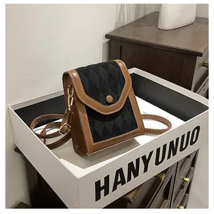 Detailed view of quilted black fabric and brown faux leather trim on a crossbody phone bag