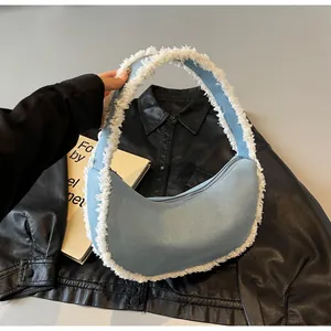 Detail of light blue denim crescent hobo bag with white faux fur fringe and chain