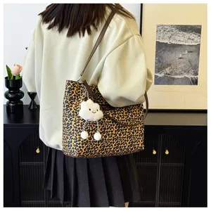 Close-up of leopard print tote bag featuring a cute white plush cloud charm and brown strap