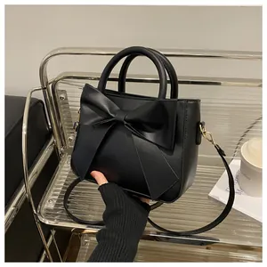 Detail of a black matte bow-knot square handbag featuring gold-tone metal hardware