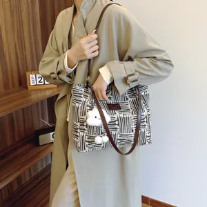 Women's canvas tote bag with black radial stripes and leather handles shown on model