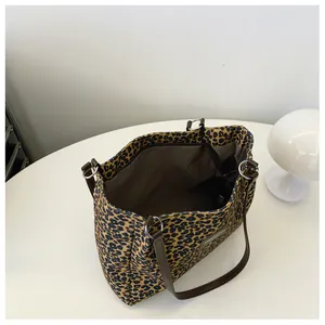 Top view of large leopard print tote bag with brown leather handles and zipper closure
