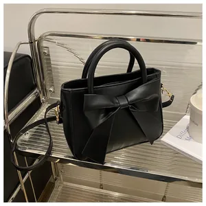 Detail of elegant black handbag with large leather bow and golden metal hardware
