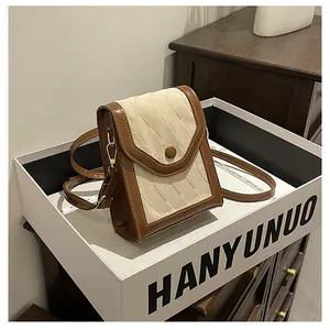 Detail of cream quilted crossbody phone bag with brown leather trim and button closure