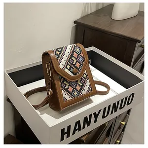 Detail of the colorful woven ethnic pattern and vintage brown leather trim on the crossbody bag