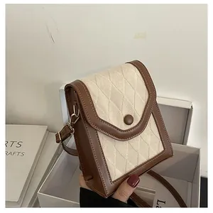 Detail of the vintage textured crossbody bag with cream quilted fabric and brown trim