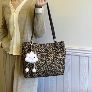 Leopard print canvas tote bag with brown straps and white plush smiley cloud charm