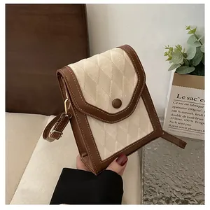 Detail of a brown leather and beige quilted crossbody bag showing the decorative button