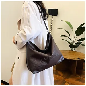 Detail of dark chocolate faux leather tote bag with FASHION embossed texture and wide strap