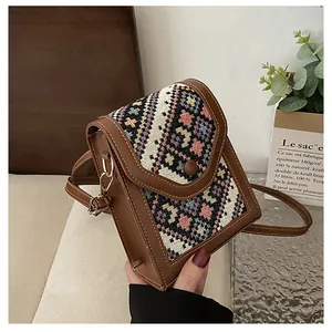 Detailed close-up of a woven geometric pattern crossbody bag with brown leather trim