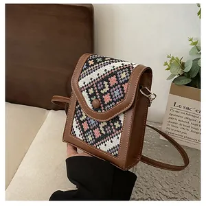 Detail of vintage crossbody phone bag with leather and ethnic woven fabric texture