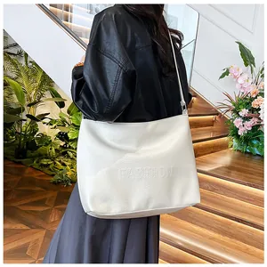 Detail of white large tote bag with embossed fashion lettering and pebbled leather texture