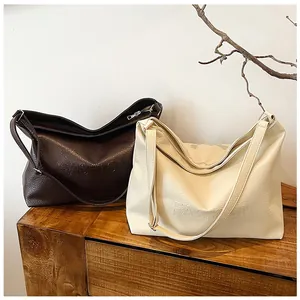 Detail of large textured leather tote bags in coffee and beige with embossed fashion text