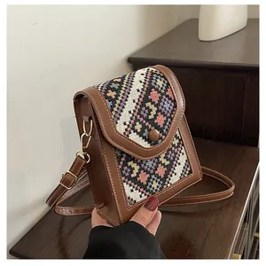 Detailed view of mini crossbody bag featuring ethnic woven pattern and premium brown leather