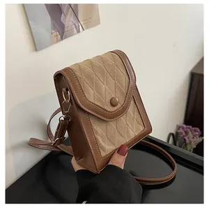 Detail view of the brown rhombic pattern texture and gold buckle on the crossbody bag