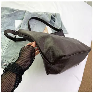 Detail of deep brown faux leather tote with litchi texture and silver buckle strap