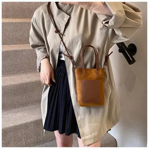 Close-up of mustard yellow suede crossbody mini bag worn with a beige wool coat
