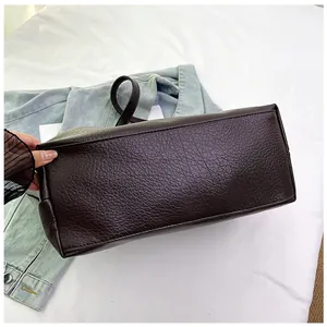 Close-up of deep brown pebbled leather texture and stitching on large tote bag base