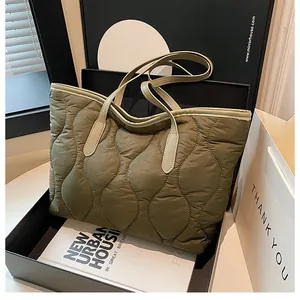 Macro detail of wave quilted puffer tote bag in olive green with cream top handles