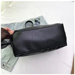 Close-up of the pebbled leather base and neat stitching on a large black tote bag