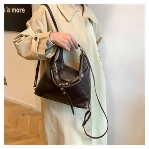 Detailed view of dark brown oil wax leather texture and embossed logo on women's retro bag